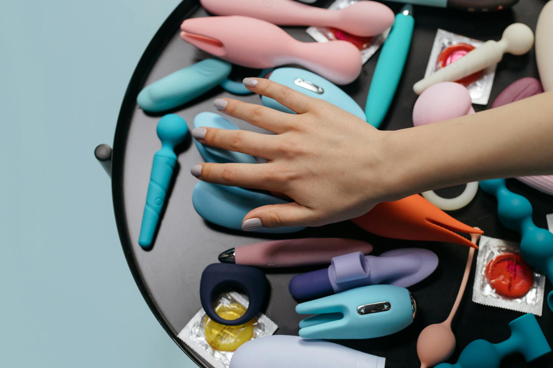 A blue silicone clitoral vibrator held in hand against a purple background, promoting self-love and sexuality.