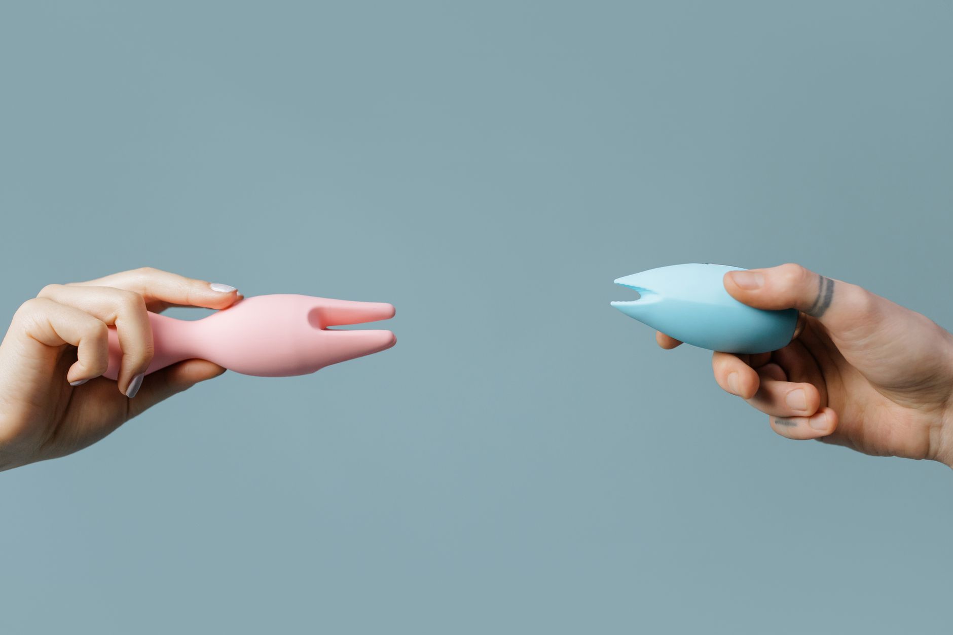 Close-up of hands holding a blue personal massager against a knitted sweater.
