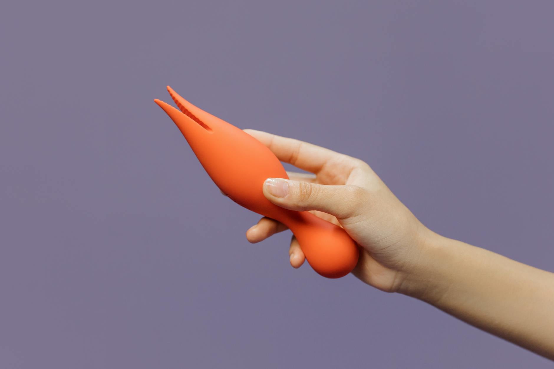Close-up of a hand holding a lemon vibrator against a purple backdrop, showcasing sensory stimulation